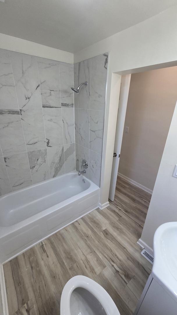 301 N W Ave, Kankakee, IL 60901 - bathroom with tub / shower combination, baseboards, wood finished floors, and toilet