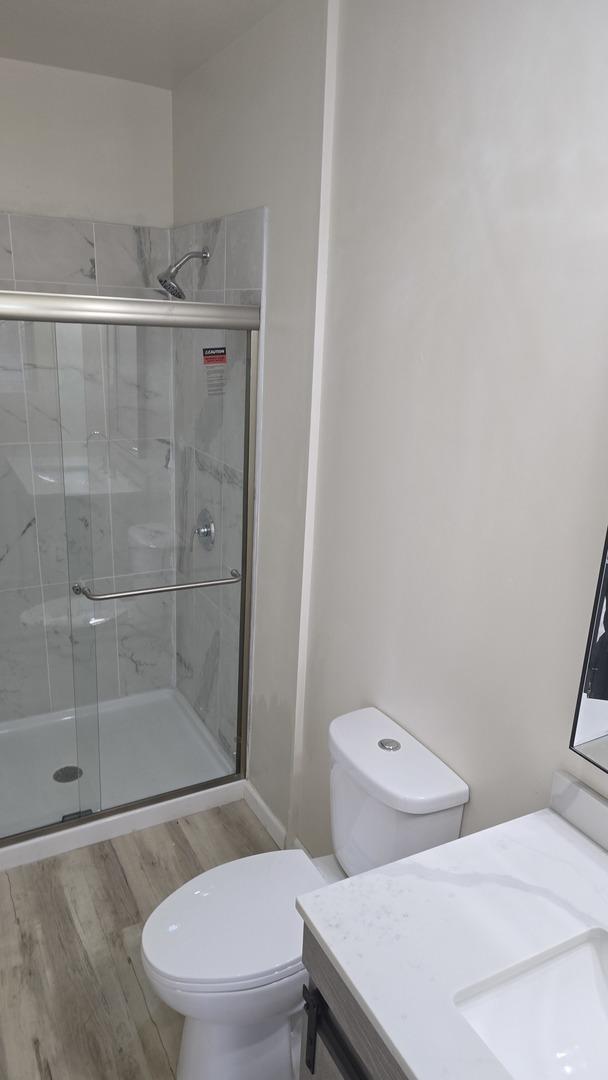 301 N W Ave, Kankakee, IL 60901 - full bath featuring a stall shower, toilet, vanity, and wood finished floors