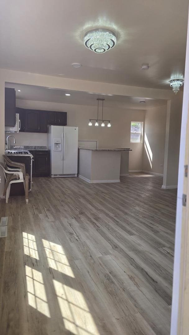 301 N W Ave, Kankakee, IL 60901 - kitchen featuring white refrigerator with ice dispenser, open floor plan, wood finished floors, and baseboards
