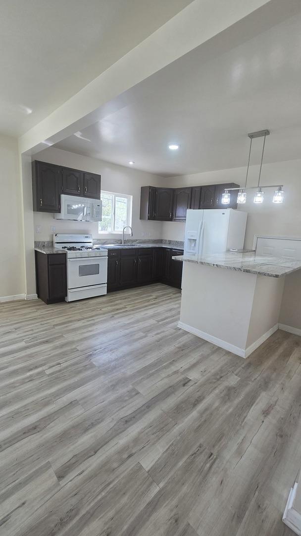 301 N W Ave, Kankakee, IL 60901 - kitchen featuring white appliances, light wood-type flooring, baseboards, decorative light fixtures, and light stone counters