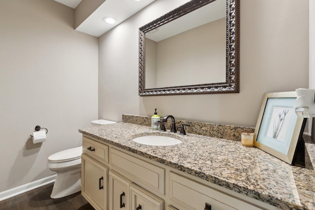 bathroom featuring toilet, vanity, baseboards, and wood finished floors