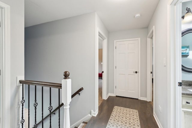 hall featuring wood finished floors, an upstairs landing, and baseboards
