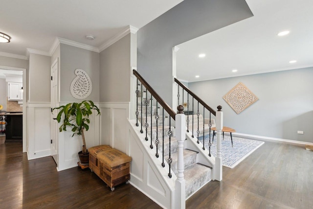 stairway with wood finished floors, a wainscoted wall, crown molding, a decorative wall, and recessed lighting