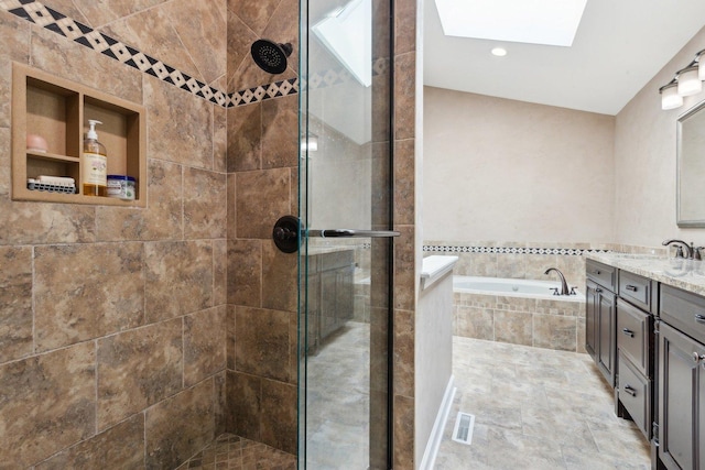 full bath featuring a shower stall, a garden tub, a skylight, vanity, and recessed lighting