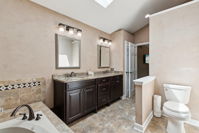 bathroom featuring toilet, lofted ceiling, a bath, double vanity, and a skylight