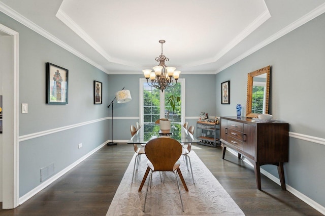 dining room featuring healthy amount of natural light, a chandelier, a raised ceiling, dark wood-style flooring, and crown molding