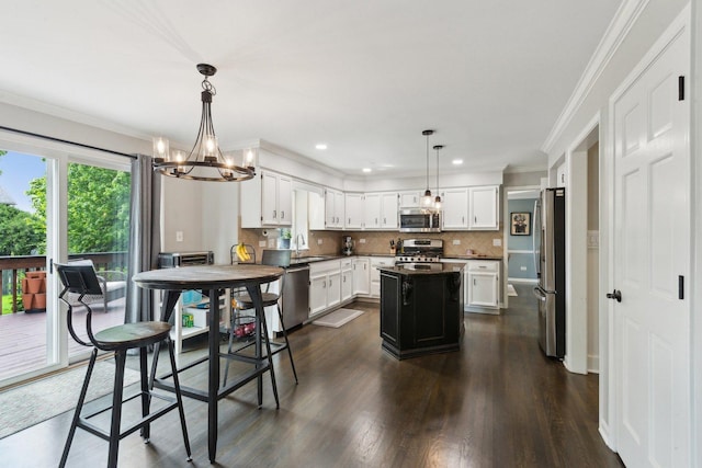 kitchen with appliances with stainless steel finishes, a chandelier, a sink, white cabinetry, and ornamental molding