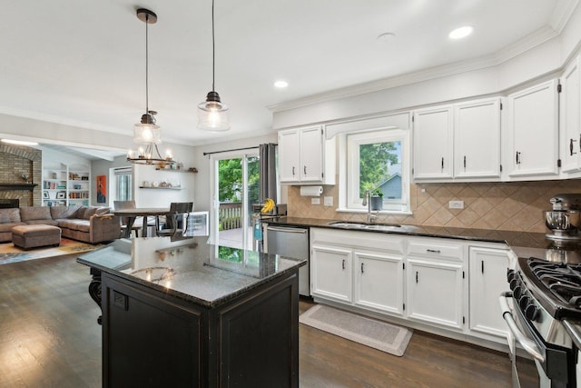 kitchen with stainless steel appliances, a sink, ornamental molding, dark wood finished floors, and white cabinets