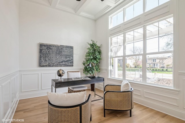 office space featuring beamed ceiling, a wealth of natural light, a decorative wall, and light wood-style floors