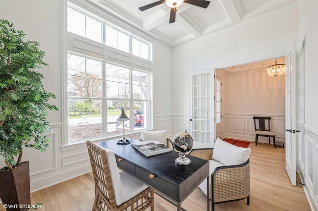 dining space with ceiling fan with notable chandelier, coffered ceiling, a decorative wall, beamed ceiling, and light wood-style floors