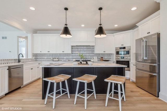 kitchen with appliances with stainless steel finishes, a kitchen island, a kitchen bar, and white cabinetry