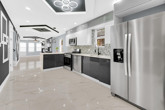 kitchen with a peninsula, marble finish floor, light countertops, modern cabinets, and appliances with stainless steel finishes