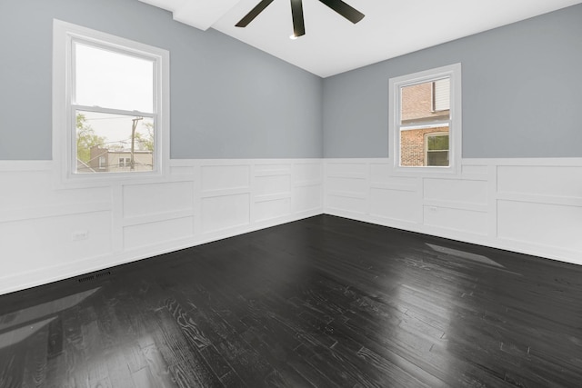 spare room featuring a ceiling fan, lofted ceiling, wainscoting, and dark wood-style floors