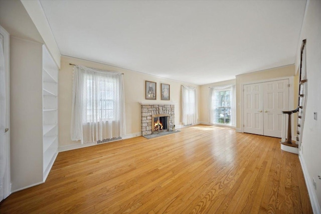 8436 Kedvale Ave, Skokie, IL 60076 - unfurnished living room with light wood-style floors, stairs, a stone fireplace, and baseboards