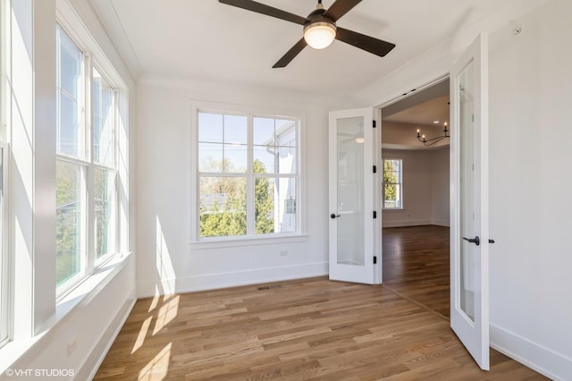 unfurnished room featuring french doors, light wood-style floors, baseboards, and a notable chandelier