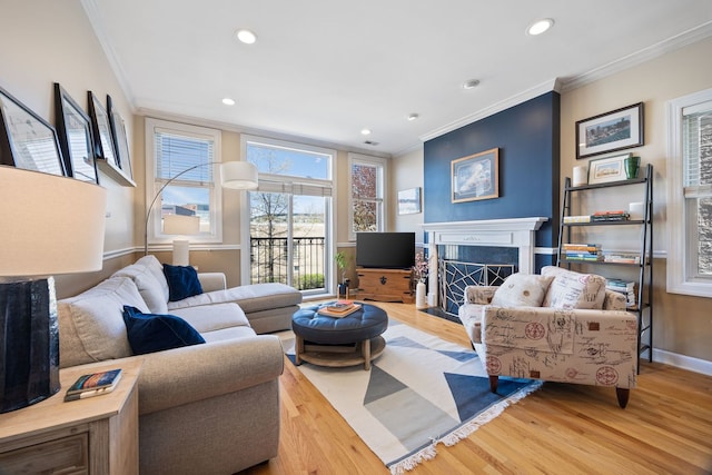 living area with ornamental molding, wood finished floors, a fireplace, recessed lighting, and baseboards