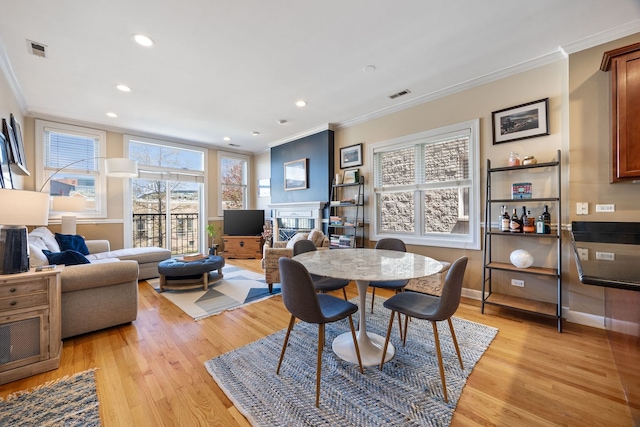 dining area featuring ornamental molding, light wood-style flooring, recessed lighting, a fireplace, and baseboards