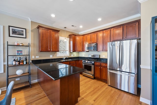 kitchen featuring appliances with stainless steel finishes, a peninsula, ornamental molding, light wood-type flooring, and hanging light fixtures