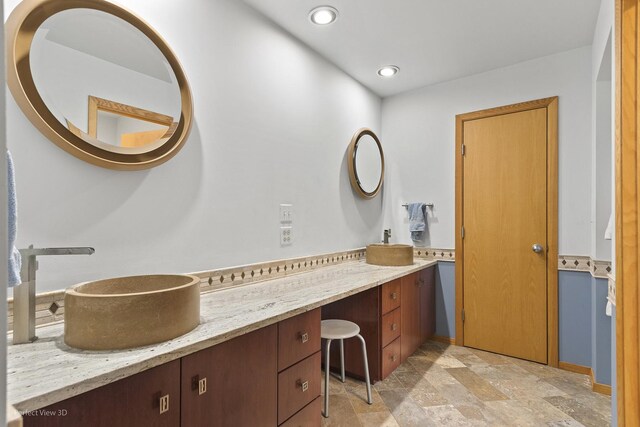 bathroom featuring stone finish floors, vanity, and recessed lighting