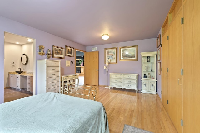 bedroom with light wood-type flooring and connected bathroom