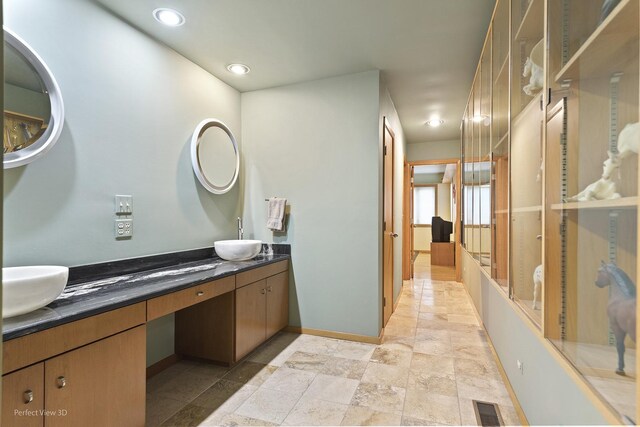 full bath featuring double vanity, stone finish flooring, recessed lighting, and baseboards
