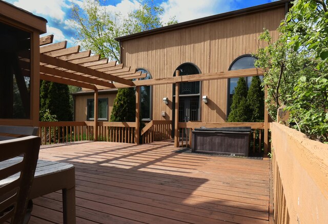 wooden deck featuring a hot tub and a pergola