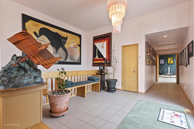 hall featuring tile patterned floors, baseboard heating, a chandelier, and baseboards