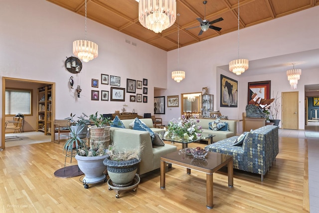 living room with wood finished floors, a chandelier, a ceiling fan, and a high ceiling