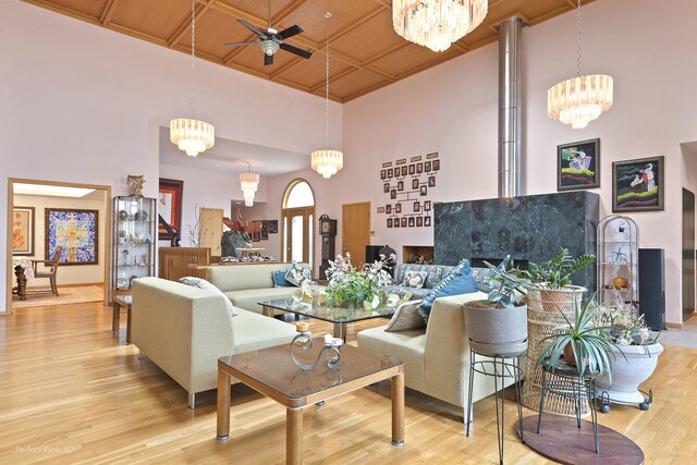 living room with ceiling fan, a high ceiling, wood finished floors, and a chandelier