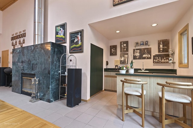 indoor bar featuring recessed lighting, a tiled fireplace, and wood finished floors