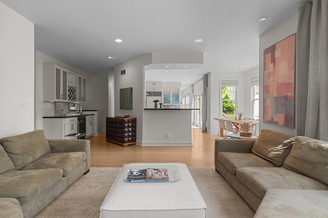living area featuring light wood-style flooring, recessed lighting, and baseboards