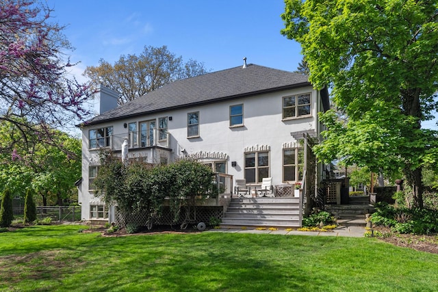 rear view of property with stucco siding, a chimney, a deck, a shingled roof, and a balcony