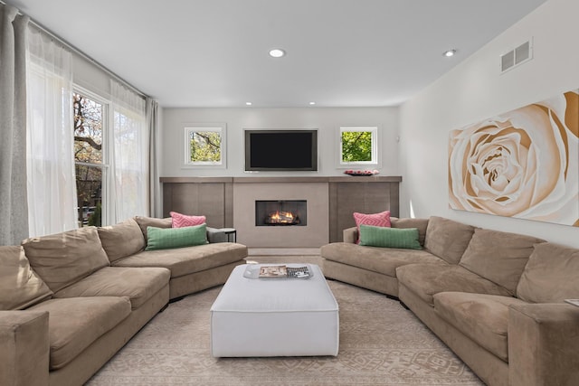 living room featuring a warm lit fireplace and recessed lighting