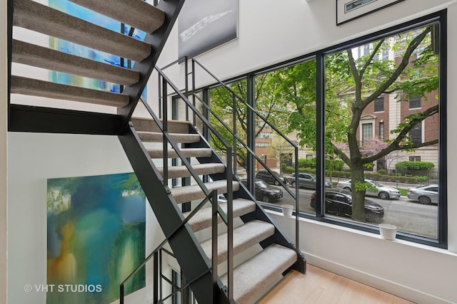stairway with wood finished floors, plenty of natural light, and baseboards