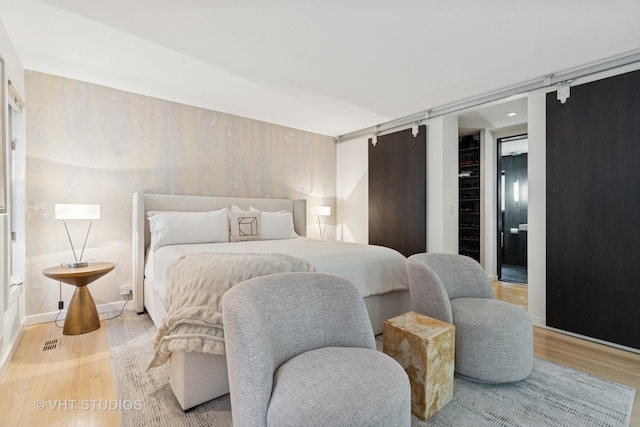 bedroom featuring wood finished floors and a barn door