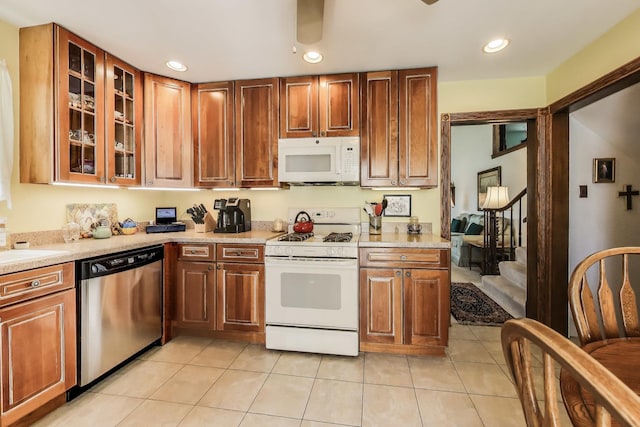 kitchen featuring white appliances, light tile patterned flooring, light countertops, recessed lighting, and glass insert cabinets