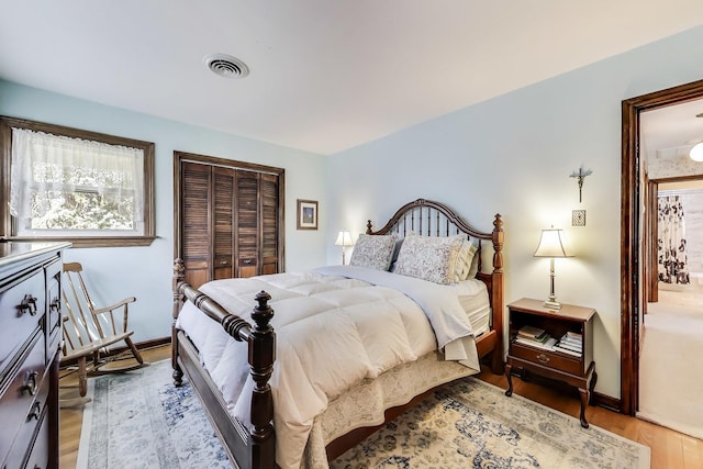 bedroom with light wood-type flooring, a closet, and baseboards