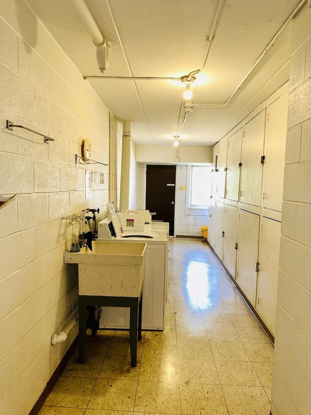 basement with washer and dryer, concrete block wall, and light floors