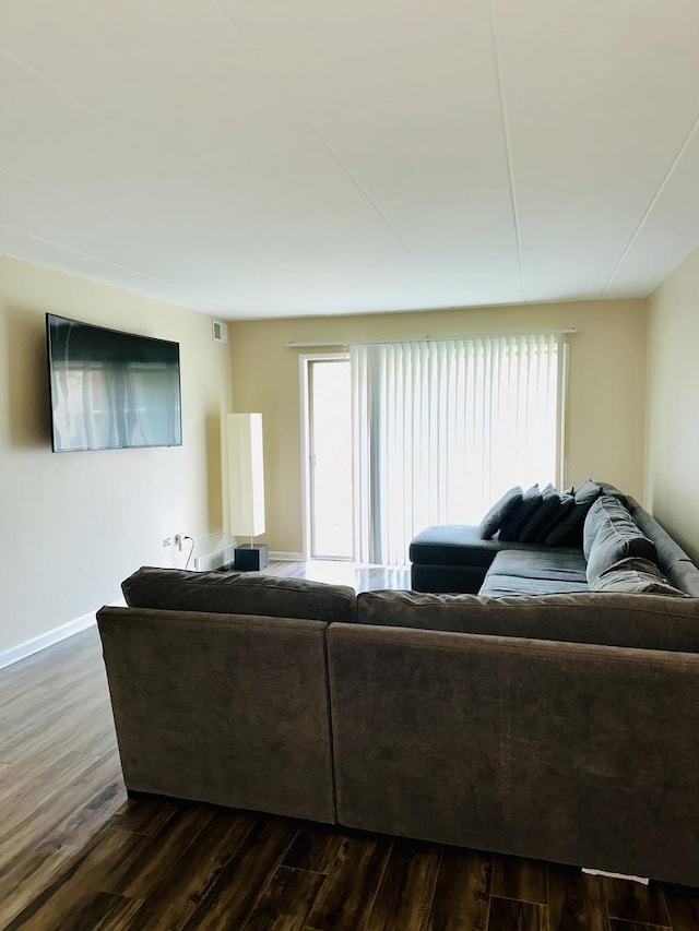 living room featuring plenty of natural light, dark wood-style flooring, and baseboards