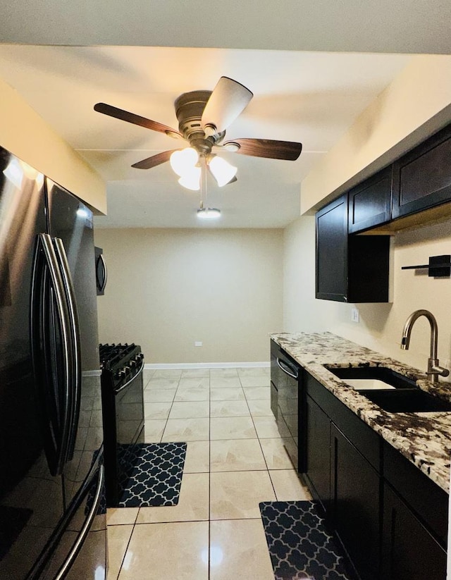 kitchen with black appliances, a sink, a ceiling fan, dark cabinets, and baseboards