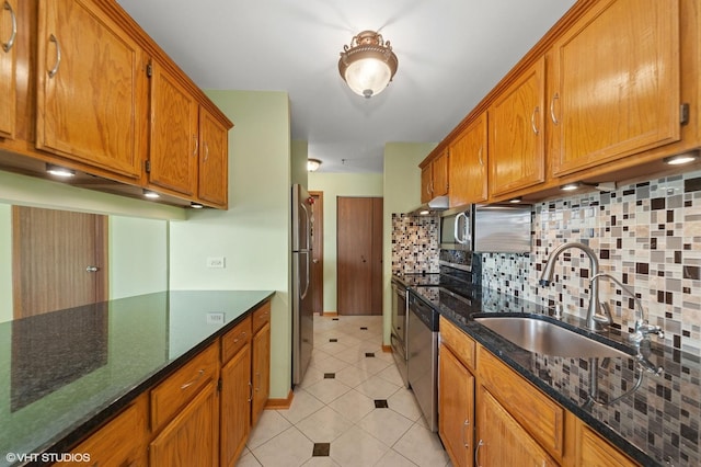 kitchen featuring a sink, appliances with stainless steel finishes, decorative backsplash, light tile patterned floors, and brown cabinets