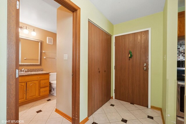 foyer entrance with light tile patterned floors and baseboards