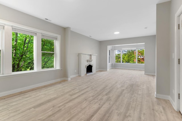 unfurnished living room with light wood finished floors, baseboards, recessed lighting, and a fireplace