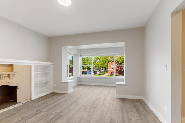 unfurnished living room with wood finished floors, a tiled fireplace, baseboards, and built in features