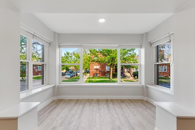 empty room featuring light wood-type flooring, plenty of natural light, and baseboards