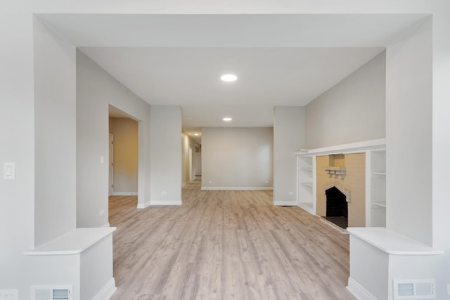 unfurnished living room with light wood-type flooring, a fireplace, baseboards, recessed lighting, and built in features
