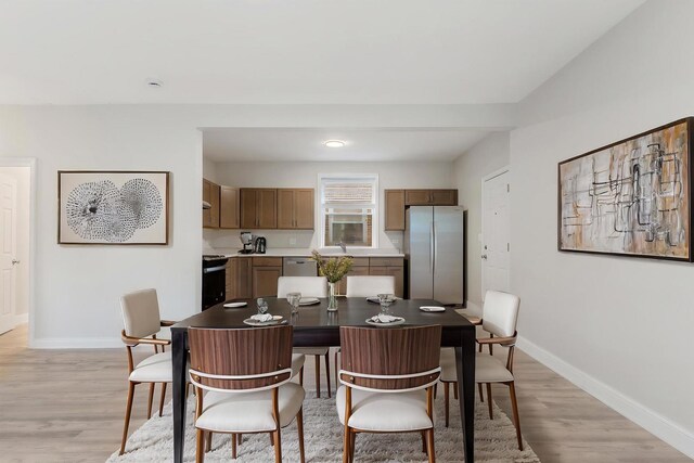 dining room featuring baseboards and light wood finished floors