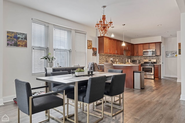 dining space featuring an inviting chandelier, baseboards, a toaster, and wood finished floors