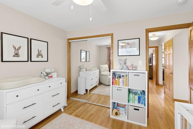 bedroom with light wood-style flooring, a closet, a ceiling fan, and baseboards