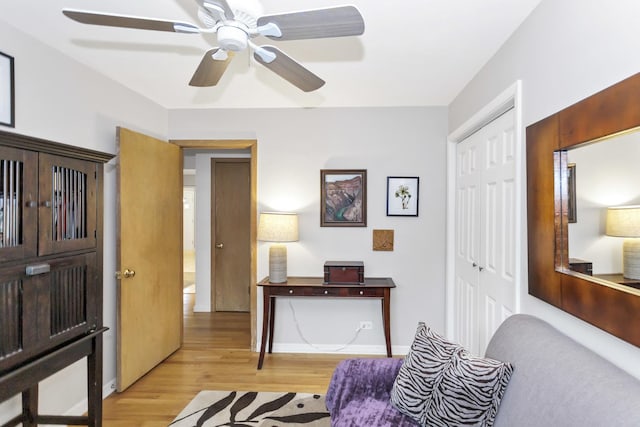 sitting room featuring light wood-style floors, a ceiling fan, and baseboards